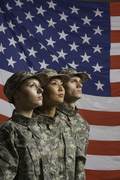 Three service members in uniform standing before the United States flag